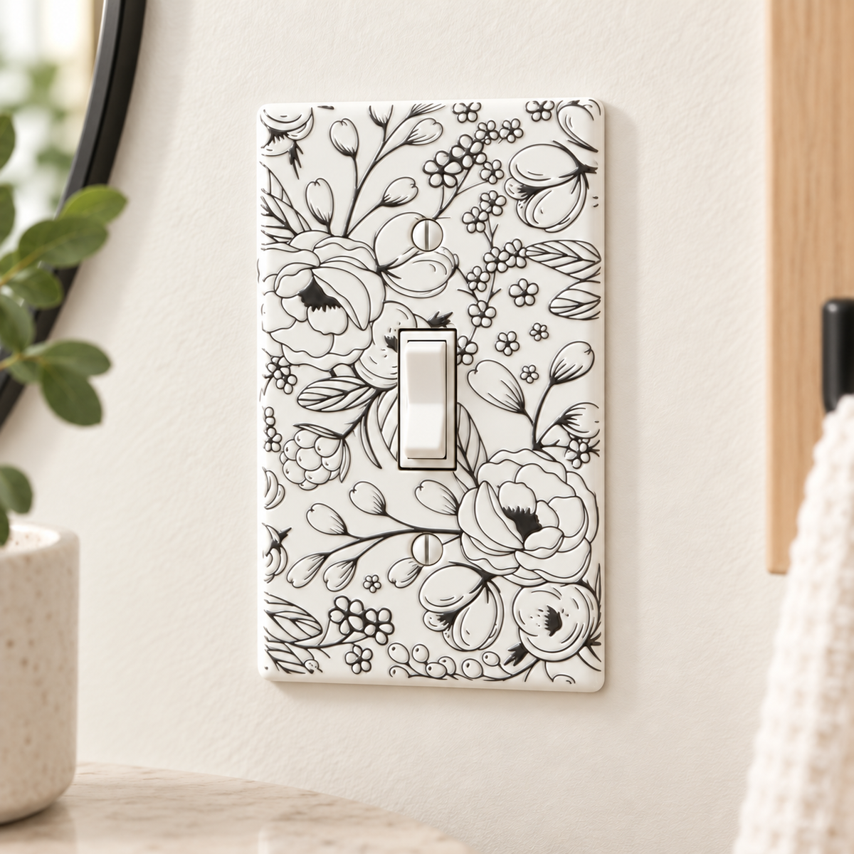 A single-toggle light switch plate with a black floral line-art pattern on a white background, mounted on a beige wall in a styled interior setting.