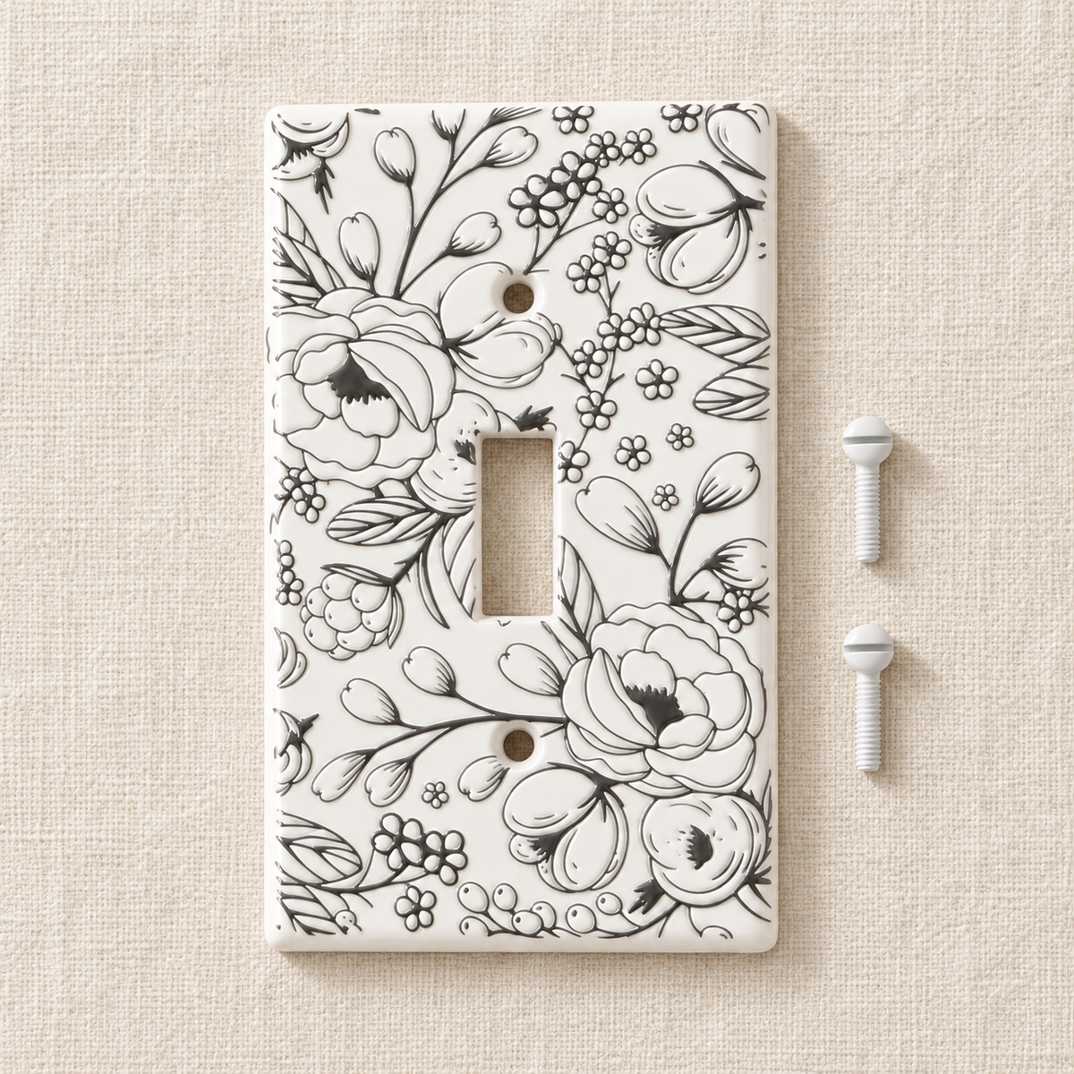 A single-toggle light switch plate cover with a black floral line-art pattern on a white background, shown with two white mounting screws on a textured beige surface.